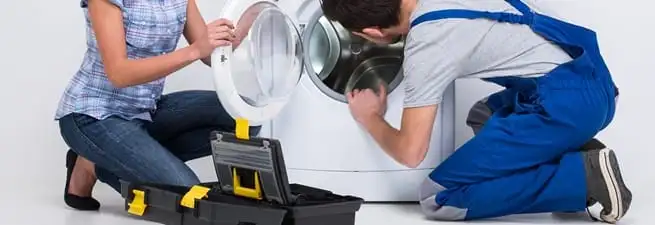 Washer repair technician inspecting a front-load washing machine with tools in Pembroke Pines, FL