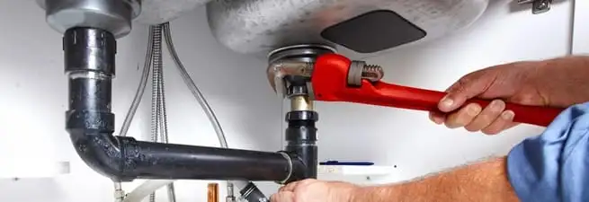 Garbage disposal repair technician tightening the sink drain and disposal connection in Pembroke Pines, FL