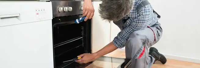 Oven repair technician inspecting and servicing an electric oven in Pembroke Pines, FL