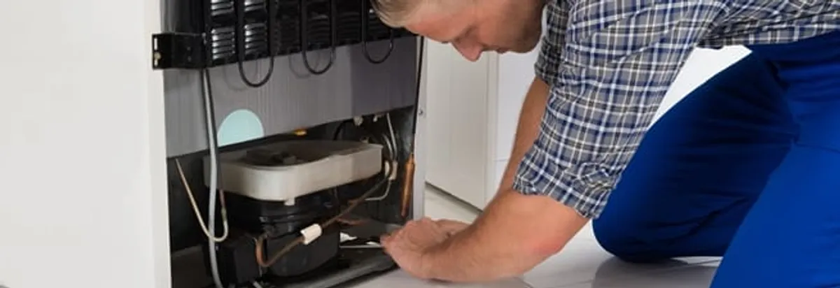 Refrigerator repair technician servicing the compressor and condenser area in Pembroke Pines, FL
