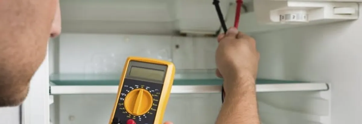 Refrigerator repair technician testing electrical components with a multimeter in Pembroke Pines, FL