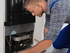 Refrigerator repair technician servicing the compressor and condenser area in Pembroke Pines, FL