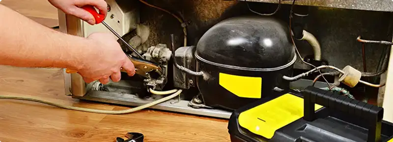 Refrigerator repair technician fixing the compressor and wiring in Pembroke Pines, FL