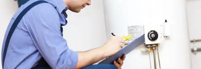 Water heater repair technician inspecting the unit and recording service notes in Pembroke Pines, FL
