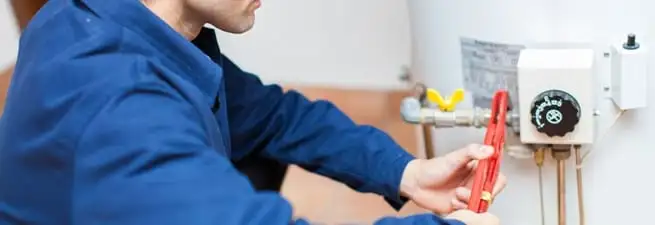 Water heater repair technician adjusting the temperature control and gas valve in Pembroke Pines, FL